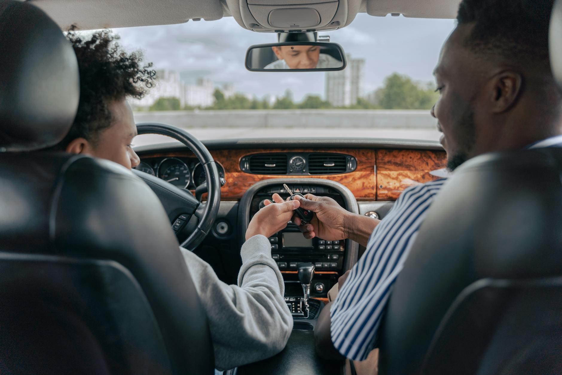 Vater und Sohn im Auto beim gemeinsamen Lernen waehrend einer Fahrstunde