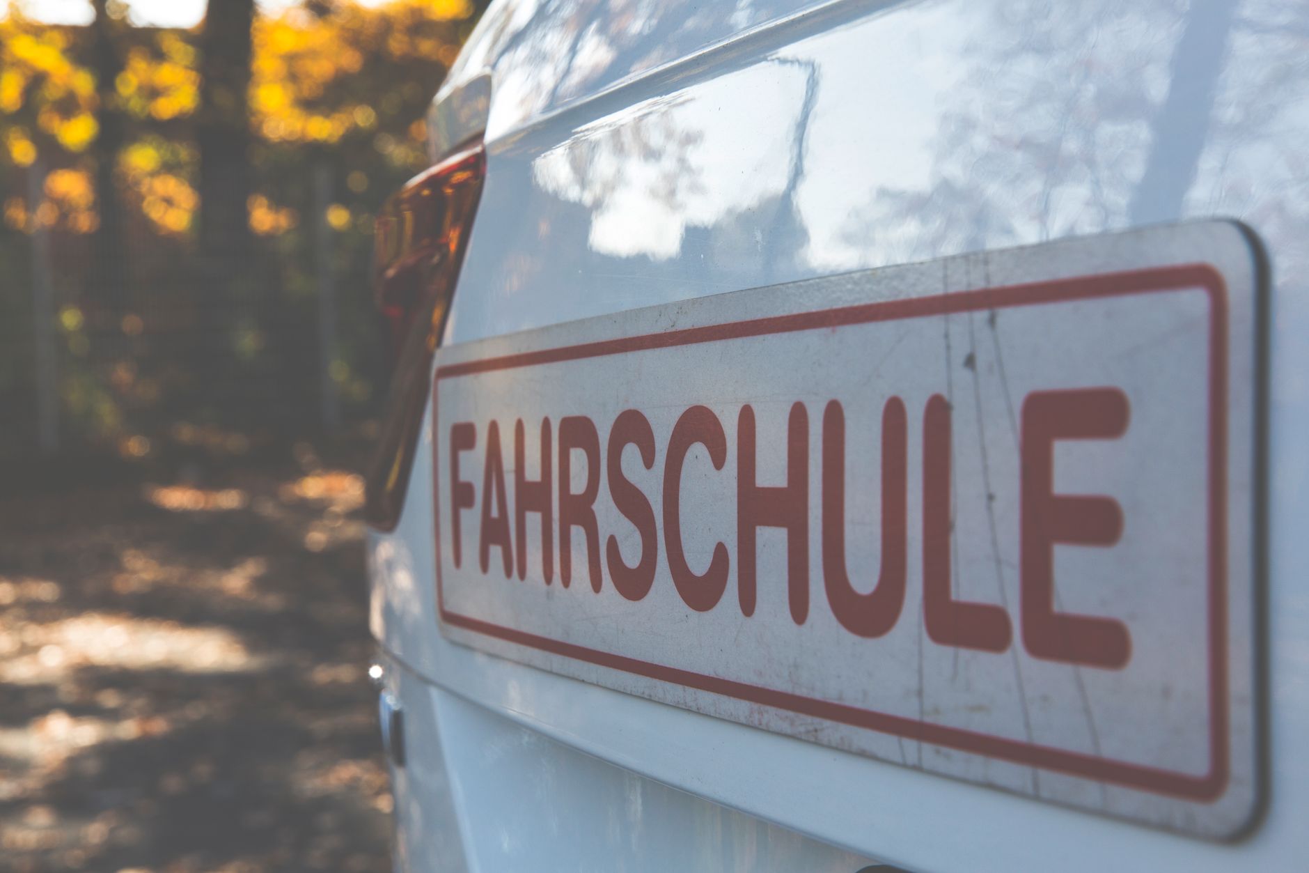 Weißes Fahrschulauto mit Fahrschule-Schild auf dem Dach
