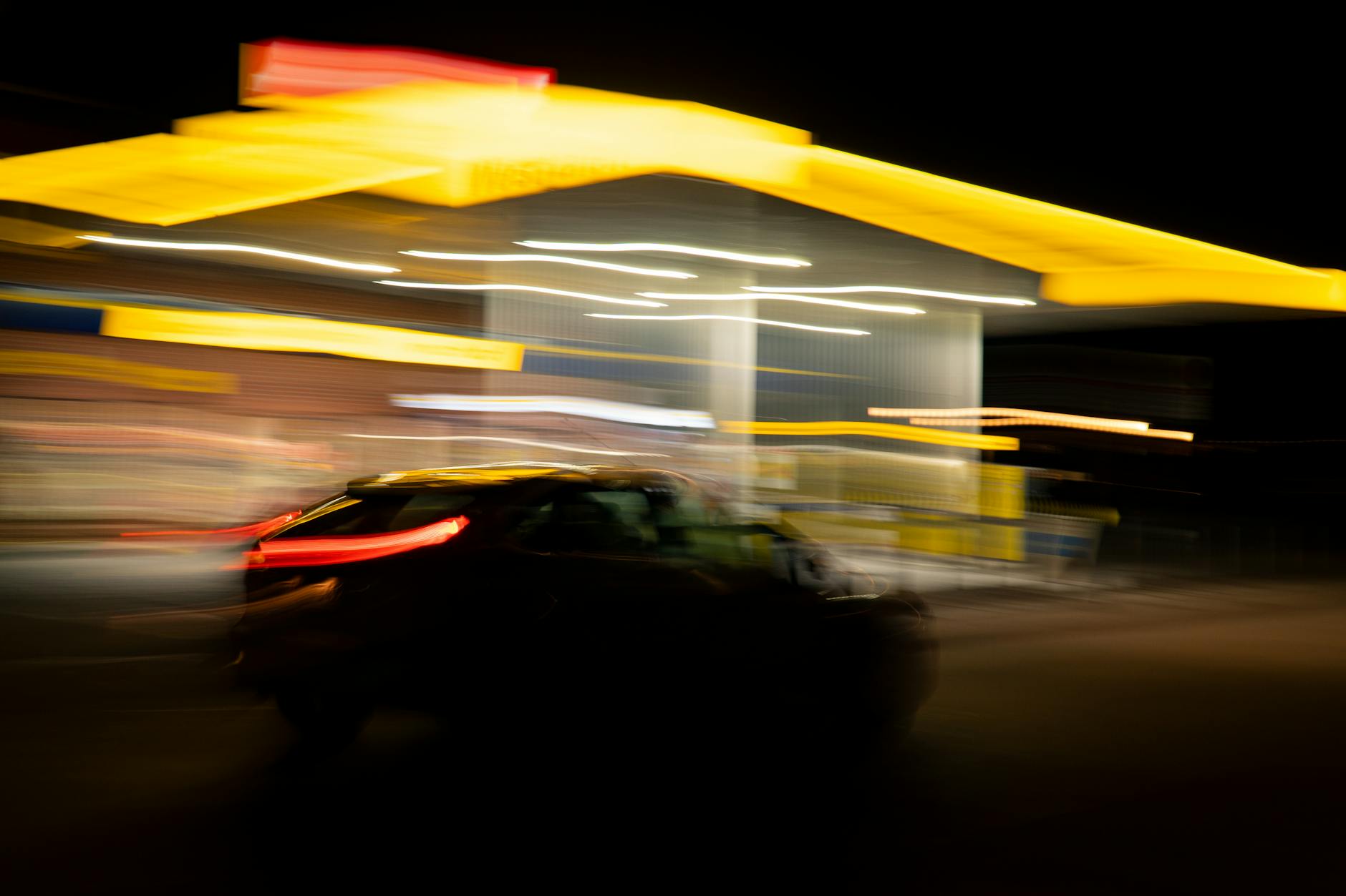 Auto in dynamischer Bewegung an einer Tankstelle bei Nacht